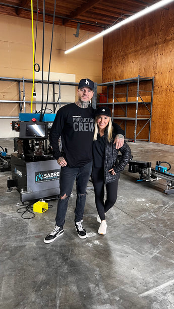 Richard Tilley and Nicole Pape standing in front of a torn down Workhorse Sabre Automatic Screen Printing Press